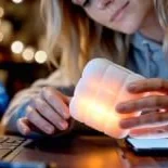 Someone at a desk in the evening, holding the glowing cube